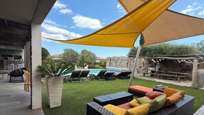 An outdoor seating area with a sofa and cushions, a pool, and a shaded area with a yellow canopy. - Casa Avvena 2 - Bed and breakfast with breakfast (Lecci)