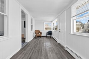 A hallway with white walls, wooden flooring, and a view of neighboring houses through the windows. - Private Pool, 3BR Jersey Shore Oasis (Seaside Heights)