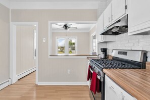 A modern kitchen with a gas stove, wooden countertop, and a view of the outdoors through a window. - Private Pool, 3BR Jersey Shore Oasis (Seaside Heights)