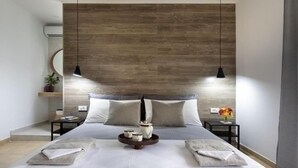 A modern bedroom with a wooden headboard, two bedside tables, a bed with pillows, a bedside lamp, and a small plant. - Santy Villa - Gerani (Gerani)