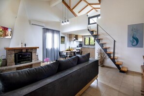 Ein modernes Wohnzimmer mit Sofa, Kamin, Essbereich, Küche und einer Treppe.