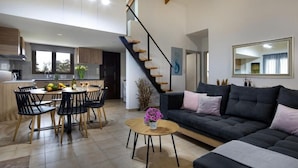 A modern living room with a sofa, coffee table, and dining area with chairs. - Santy Villa - Gerani (Gerani)