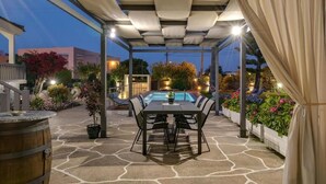 An outdoor patio with a pool, a table with chairs, and potted plants. - Santy Villa - Gerani (Gerani)