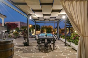 Eine Außenpatio mit Pool, Tisch und Stühlen sowie Blumentöpfen.