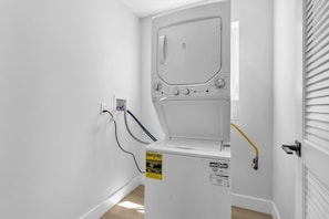 A laundry room with a washing machine, a dryer, and a hose connected to the wall.