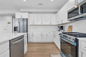 A modern kitchen with white cabinetry, stainless steel appliances, and a gas stove.