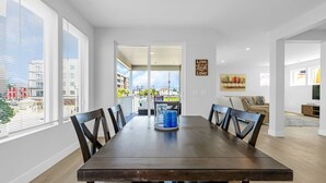 A modern dining area with a wooden table, chairs, and a view of the city through large windows.