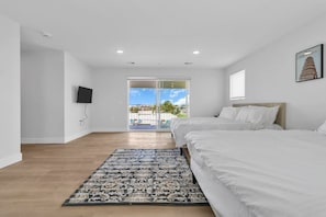 A hotel room with two beds, a TV, a large window with a view, and a patterned rug.