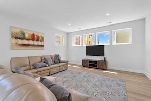 A modern living room with a sofa, a flat-screen TV, and a patterned rug.