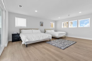 A bedroom with two beds, a nightstand, a window, and a patterned rug.