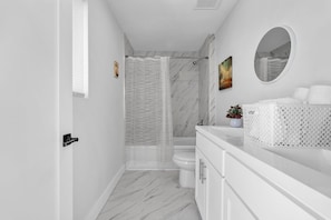 A modern bathroom with a shower, toilet, and vanity.