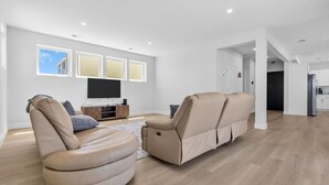 A modern living room with a sofa, TV, and a dining area.