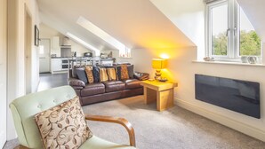 Ein Loft-Wohnbereich mit einer Couch, einem Holztisch mit Lampe und einem großen Fenster.