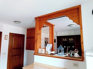 Een houten spiegel met een decoratieve metalen lijst, een klein plankje met een beeldje, en een apparaat van Bosch.