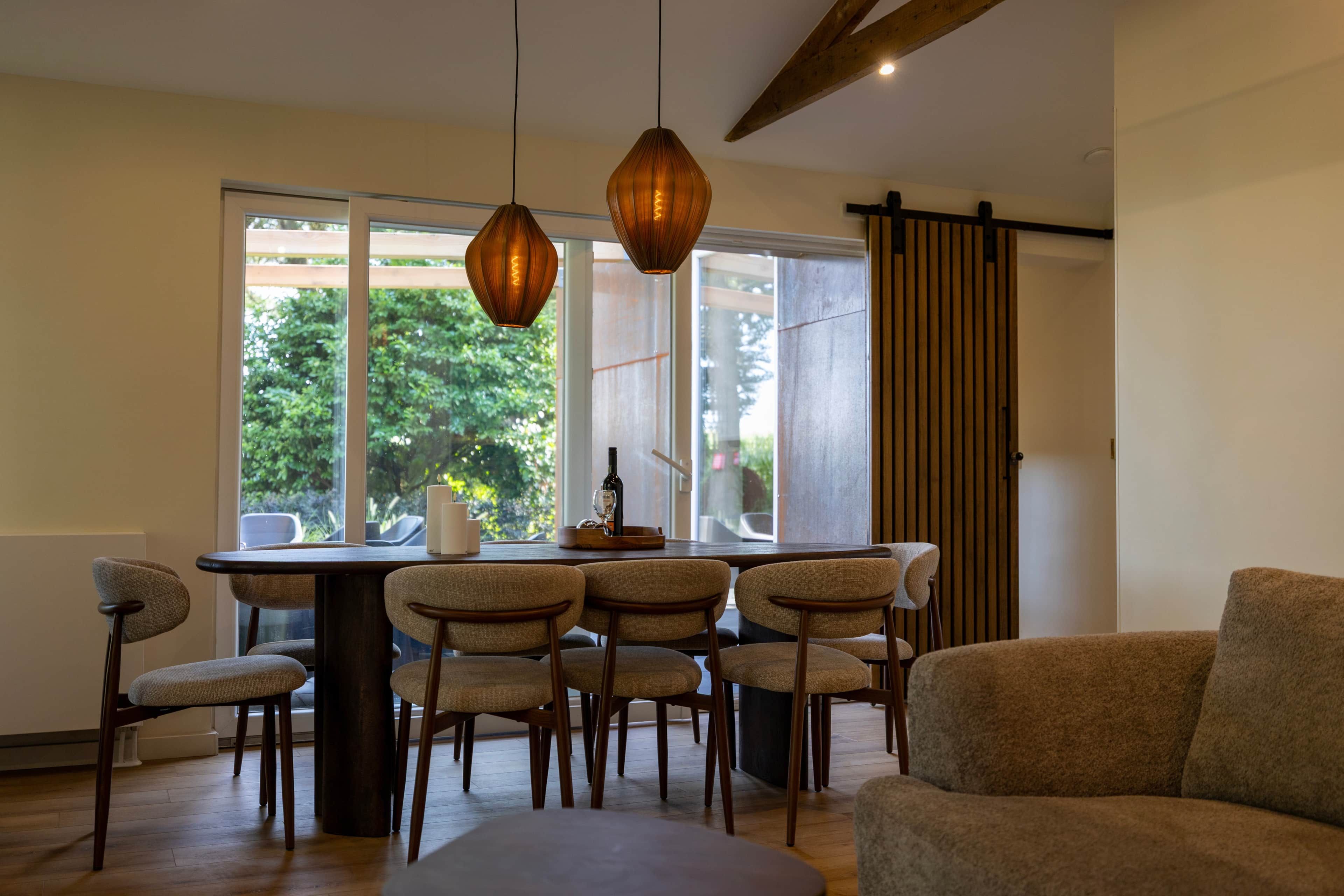 A dining area with a table and chairs, a bottle of wine, and a candle on the table.