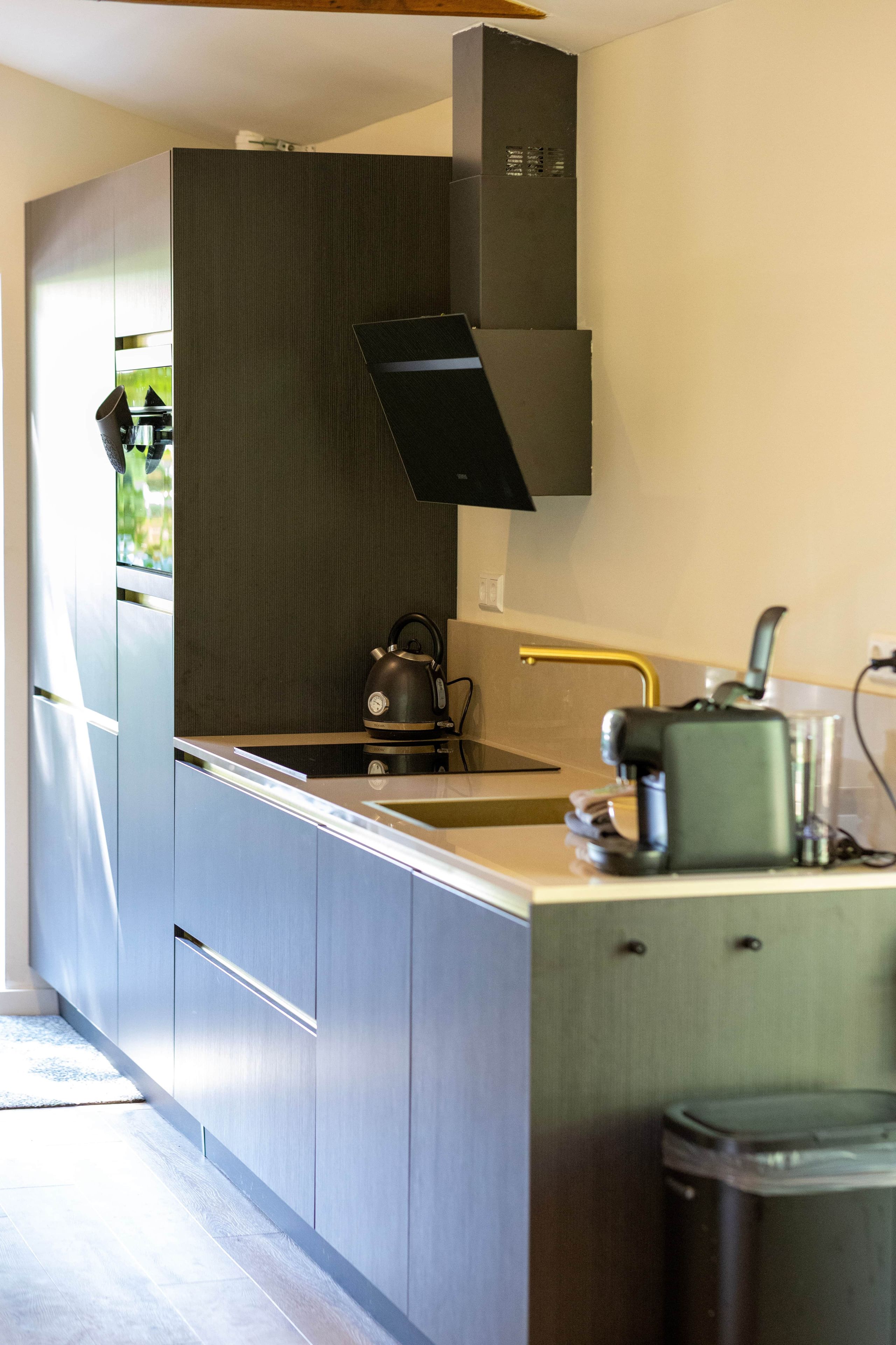 A modern kitchen with a stainless steel range hood, a kettle, and a coffee machine.