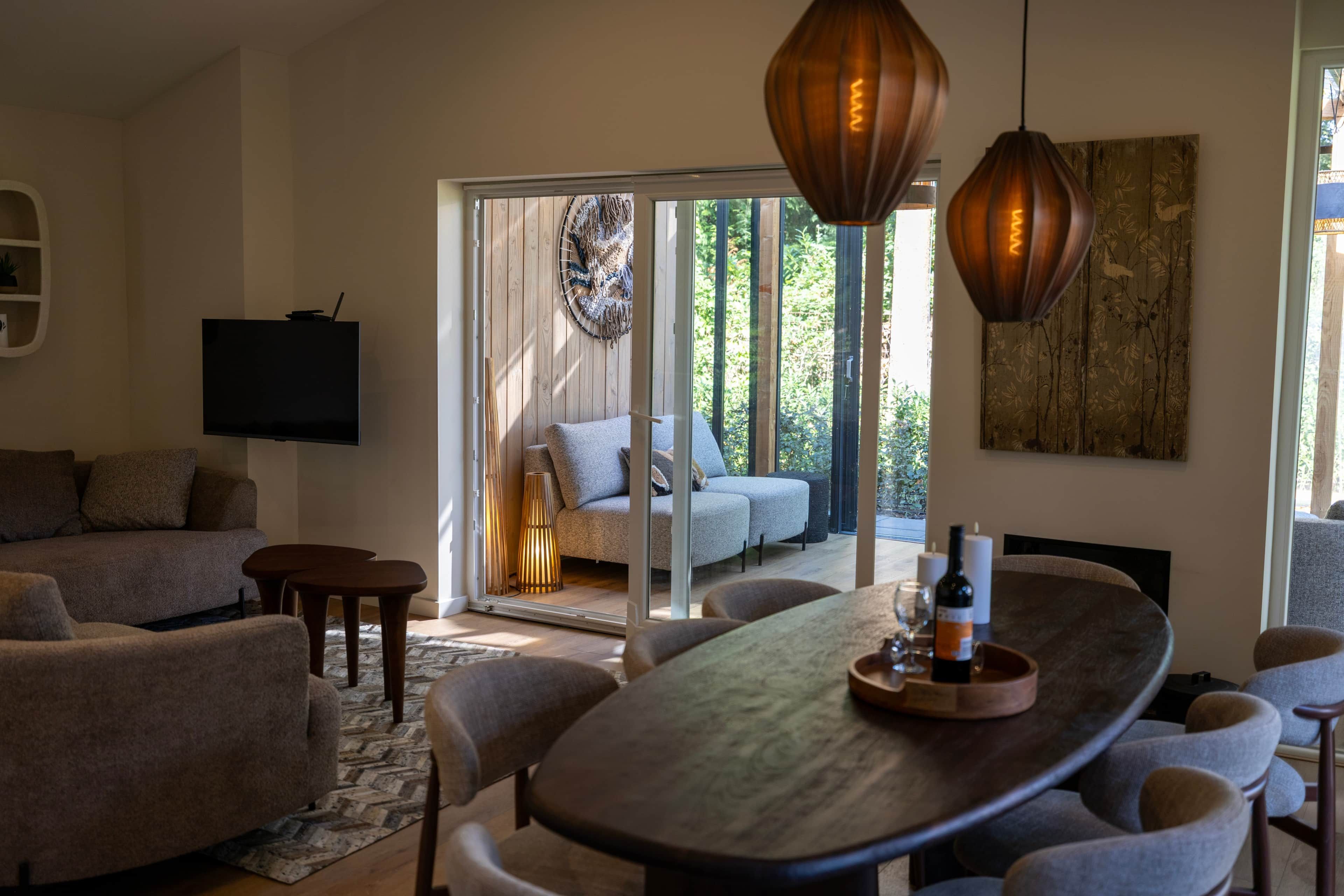 A modern living room with a large dining table, sofas, and a television.