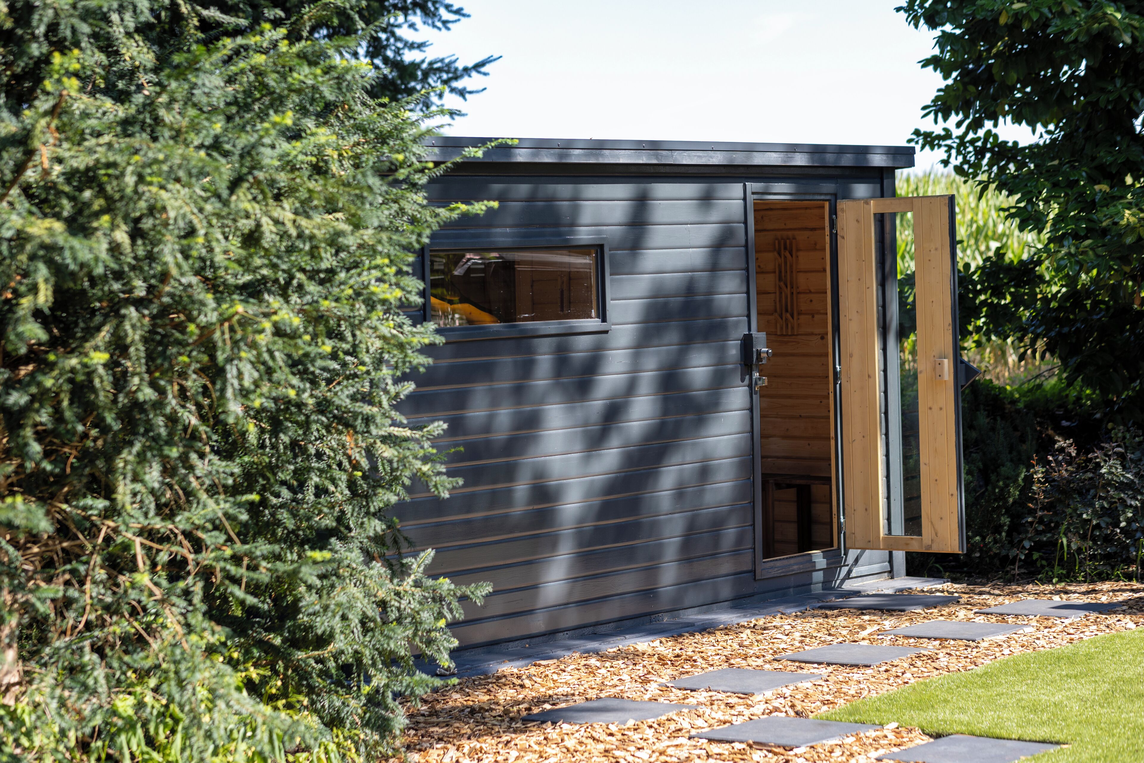 A modern building with a wooden door, a window, and a pathway leading to it.