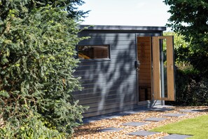 A modern building with a wooden door, a window, and a pathway leading to it.
