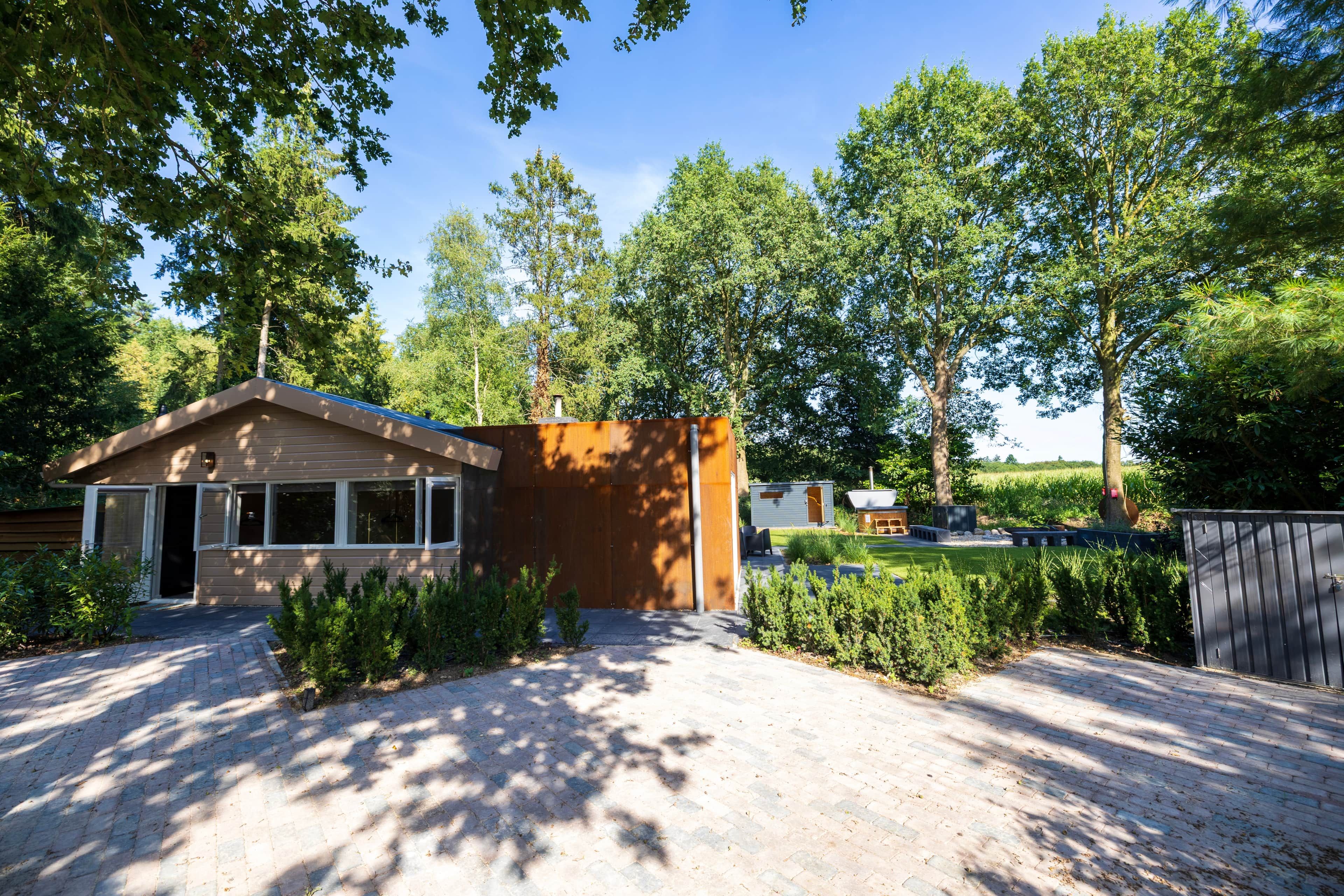 Una casa moderna con entrada pavimentada, cerca de madera y un pequeño jardín.
