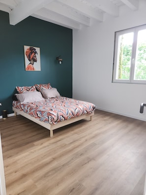 Une chambre à coucher avec un lit, une fenêtre et un mur orné d’un tableau.