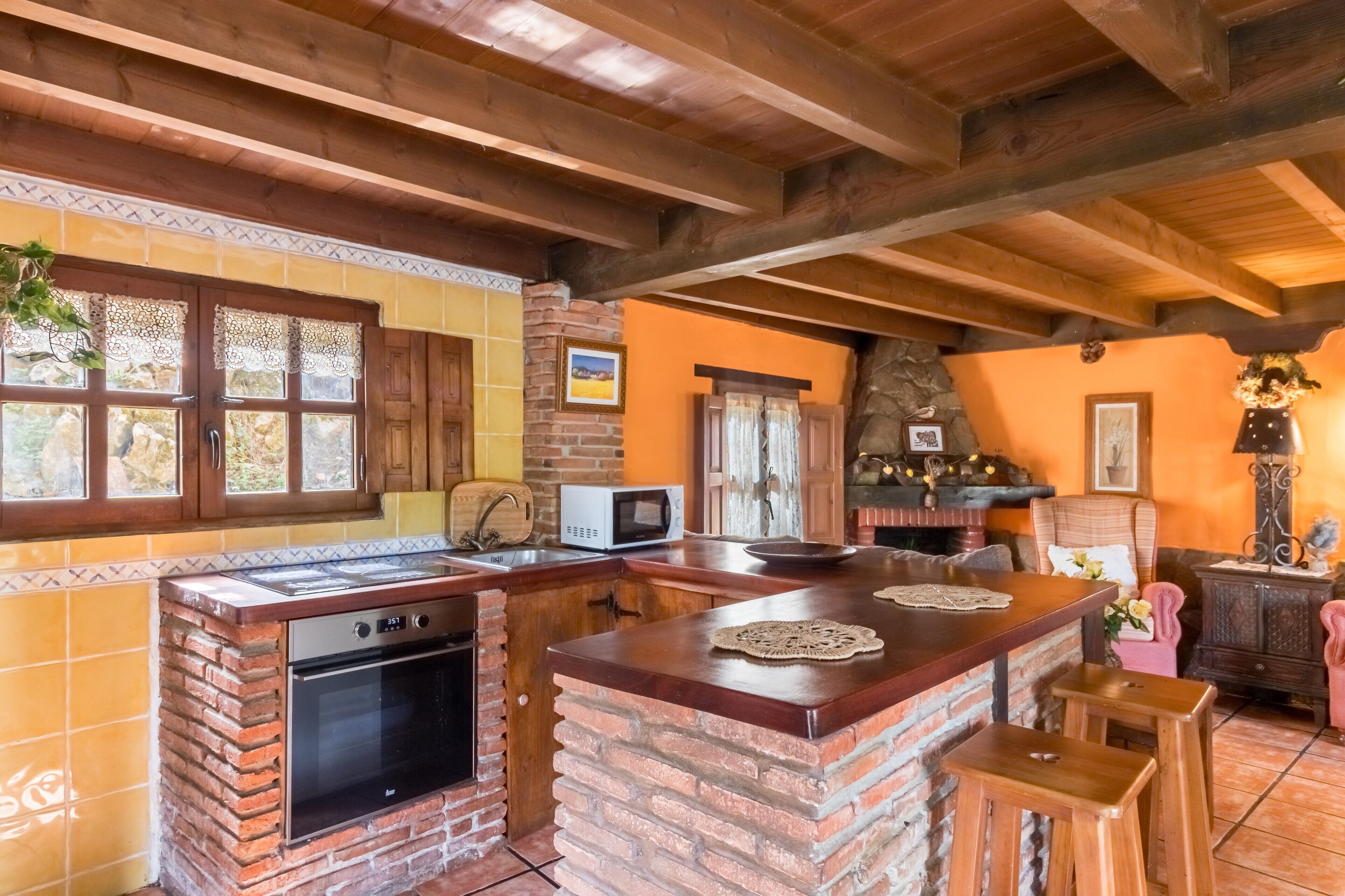Una cocina con una isla de ladrillo, armarios de madera, un microondas y una pared de piedra.
