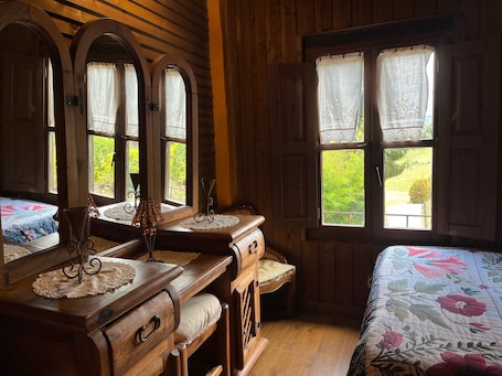 A wooden room with a bed, a dresser, and a window with curtains.. The Postman's Cottage in Camijanes