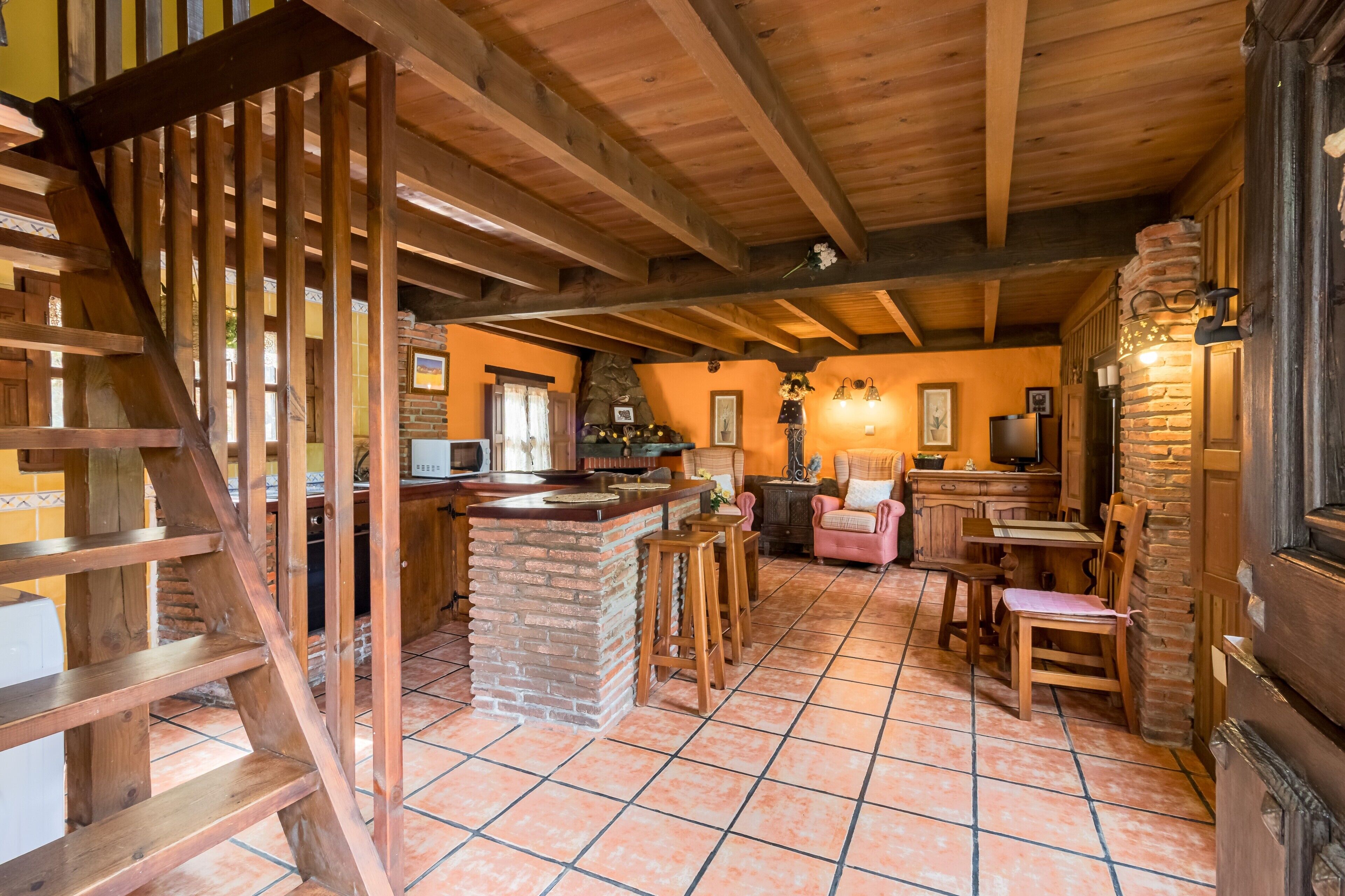 A rustic interior with exposed wooden beams, a stone fireplace, and a bar area.
