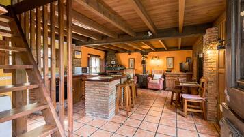 A rustic interior with exposed wooden beams, a stone fireplace, and a bar area.