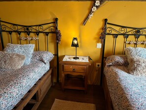 Un dormitorio con dos camas, una mesita de noche, una lámpara y piñas decorativas.