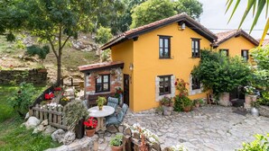 A yellow house with a stone patio, outdoor seating, and potted plants.