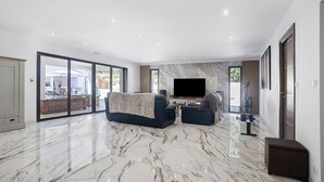 Uma sala de estar ampla com uma televisão grande, um sofá e uma mesa de centro.