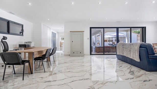 Um interior moderno com área de jantar, um sofá e uma porta de vidro deslizante que dá para um pátio.