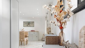 Um interior moderno com uma sala de jantar branca, um vaso com flores secas e um objeto de decoração rústico.