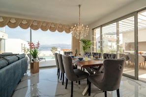 Ein moderner Essbereich mit einem großen Tisch, Stühlen und einer Chandelier.
