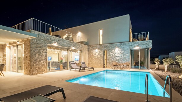 Uma casa moderna com piscina, fachada de pedra e varanda com área de estar externa.