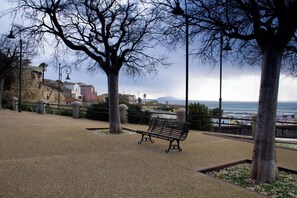 Eine Parkbank mit Blick auf eine Küstenlandschaft und Gebäude im Hintergrund.