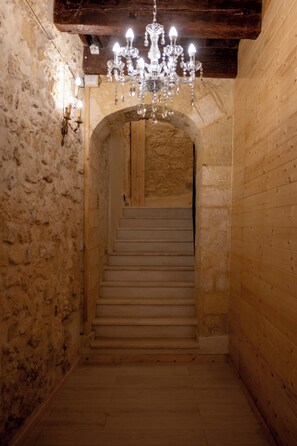 Eine Treppe mit einer Chandelüster, Steinwänden und Holzvertäfelung.