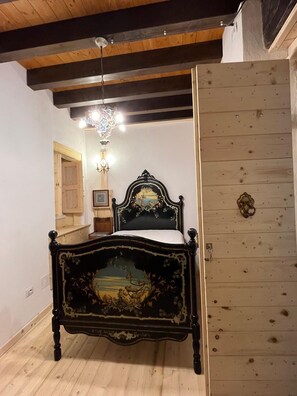 Ein Schlafzimmer mit einem hölzernen Bett, einer Kristallleuchtre, einer Tür und einem Holzboden.