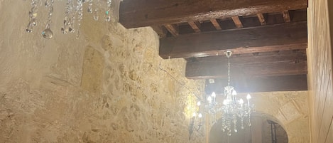Un corridoio con pareti in pietra, soffitto in legno e lampadari.