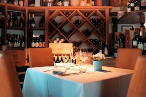 Ein Restaurantambiente mit gedecktem Tisch, Weinflaschen im Hintergrund und einer blauen Tischdecke.