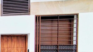 A building facade with a wooden door, a window with horizontal blinds, and a vent above the door. - New!!! Loft Córdoba Home (Córdoba)