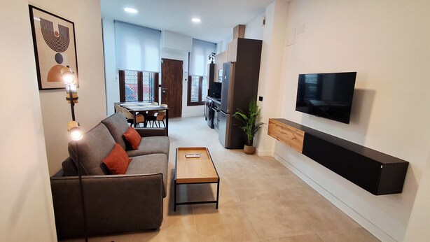A modern living room with a sofa, coffee table, TV, and dining area. - New!!! Loft Córdoba Home (Córdoba)