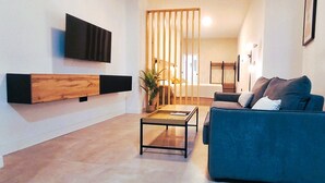 A modern living room with a blue sofa, a coffee table, and a TV mounted on the wall. - New!!! Loft Córdoba Home (Córdoba)