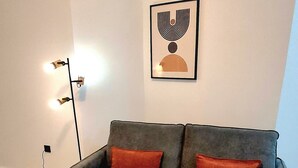 A modern living room with a grey sofa, red cushions, a wooden coffee table, a framed abstract artwork, and a wall-mounted air conditioner. - New!!! Loft Córdoba Home (Córdoba)