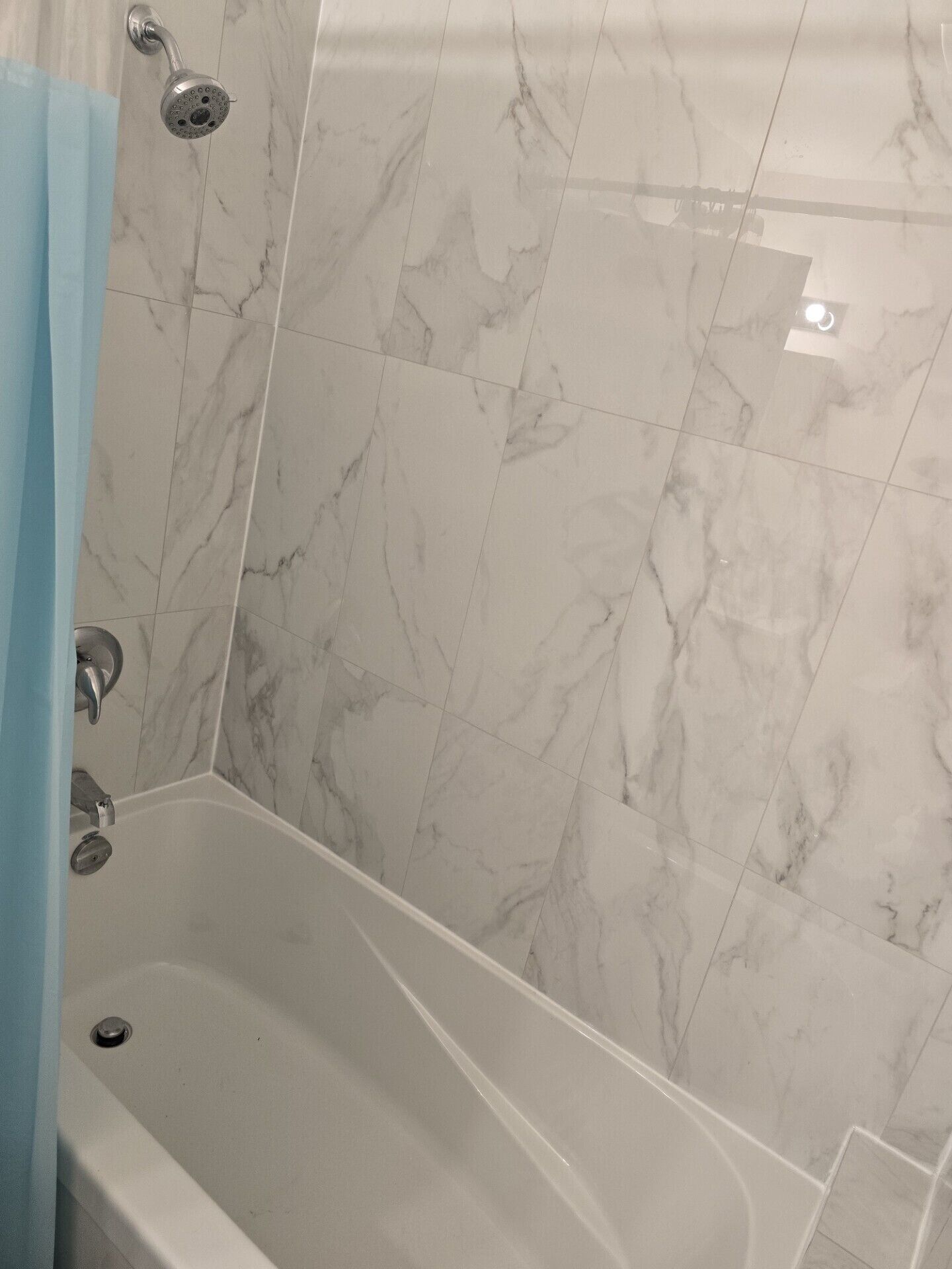 Ein Badezimmer mit einer Badewanne, einer Duschbrause und Marmorfliesen.