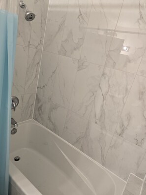Une salle de bain avec une baignoire, une douche et des carreaux de marbre.