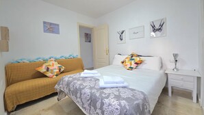 Un dormitorio con cama, sofá, mesita de noche y puerta.