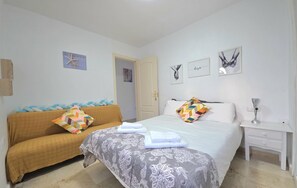 Une chambre à coucher avec un lit, un canapé, une table de chevet et une porte.