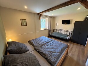 Un dormitorio con cama, ventana, televisor y armario.